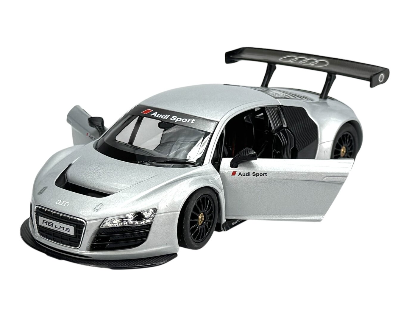 Srebrny model samochodu wyścigowego z otwartymi drzwiami i widocznym napisem \'Audi Sport\' na przedniej szybie. Na przodzie znajduje się tablica z napisem \'R8 LMS\'.