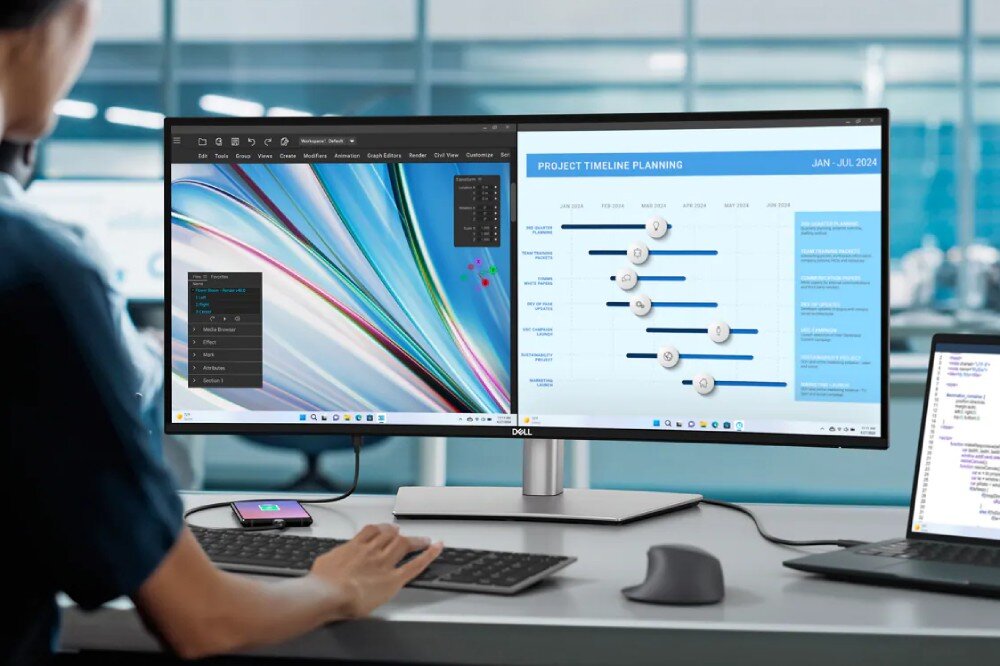 Monitor DELL z wyświetlanym kolorowym wzorem i wykresem z napisem \'PROJECT TIMELINE PLANNING JAN - JUL 2024\'. Na biurku znajduje się klawiatura, mysz i laptop.