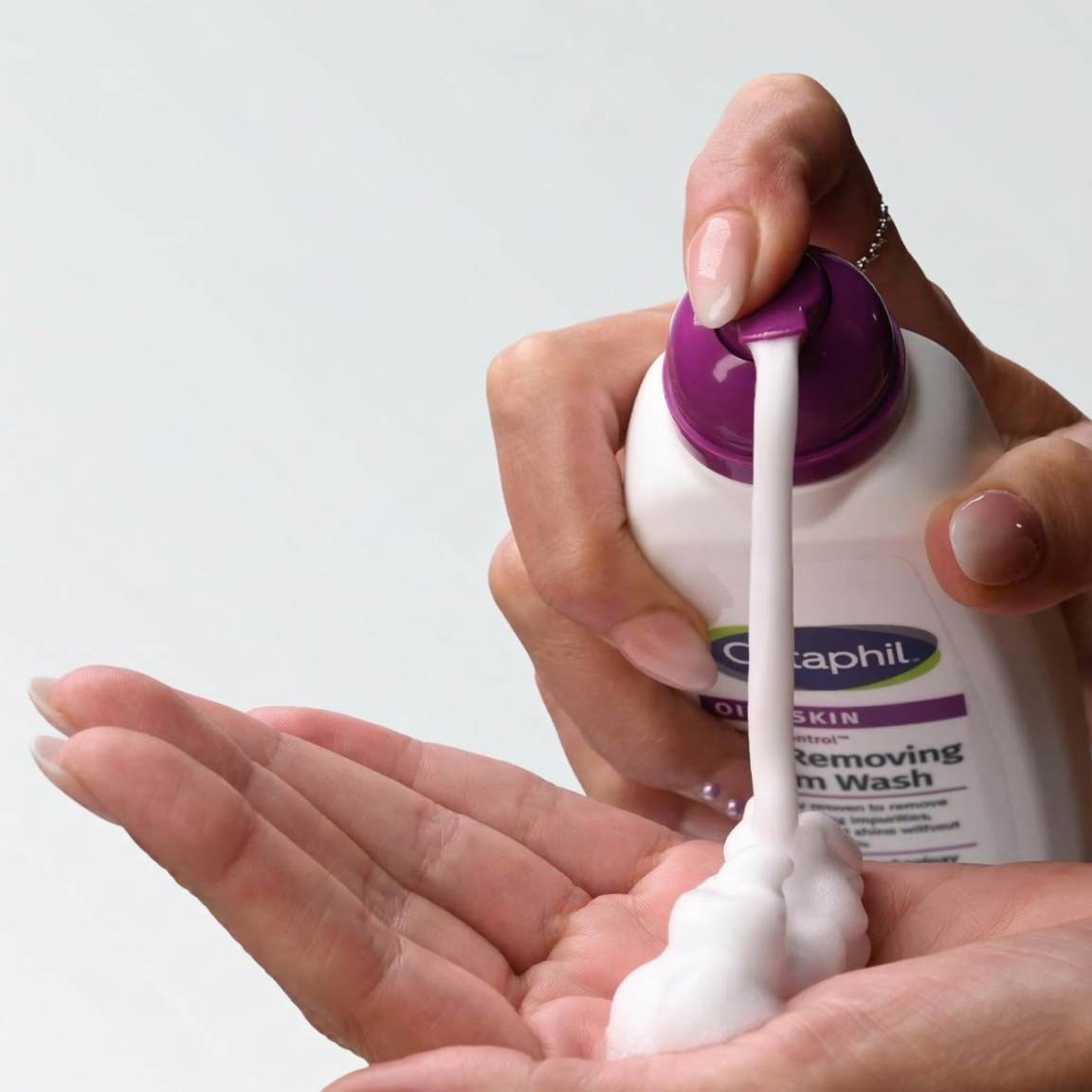 Osoba wyciska piankę z butelki z napisem \'Cetaphil\' na dłoń. Na etykiecie widoczny jest tekst \'Oily Skin\' oraz \'Foam Wash\'.