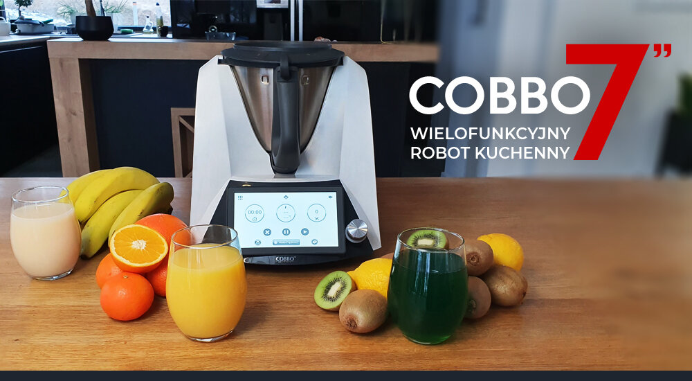 Na drewnianym blacie stoi wielofunkcyjny robot kuchenny COBBO 7 z wyświetlaczem dotykowym, otoczony owocami i szklankami z sokami. Obok urządzenia widoczny jest napis: \'COBBO 7 WIELOFUNKCYJNY ROBOT KUCHENNY\'.