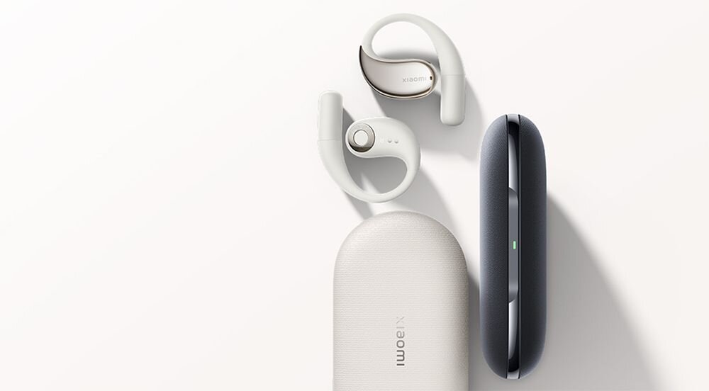 Na obrazie widoczne są beżowe słuchawki douszne z zaokrąglonymi pałąkami oraz dwa etui, jedno w kolorze beżowym z napisem \'xiaomi\', a drugie w kolorze ciemnoszarym.