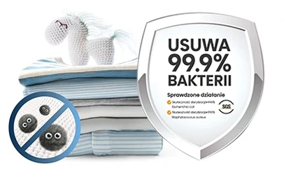 Na obrazie widoczny jest stos złożonych ręczników z pluszowym jednorożcem na górze oraz tarcza z napisem \'USUWA 99.9% BAKTERII\'. Obok znajduje się okrągły symbol z przekreślonymi bakteriami i tekstem \'Sprawdzone działanie\'.