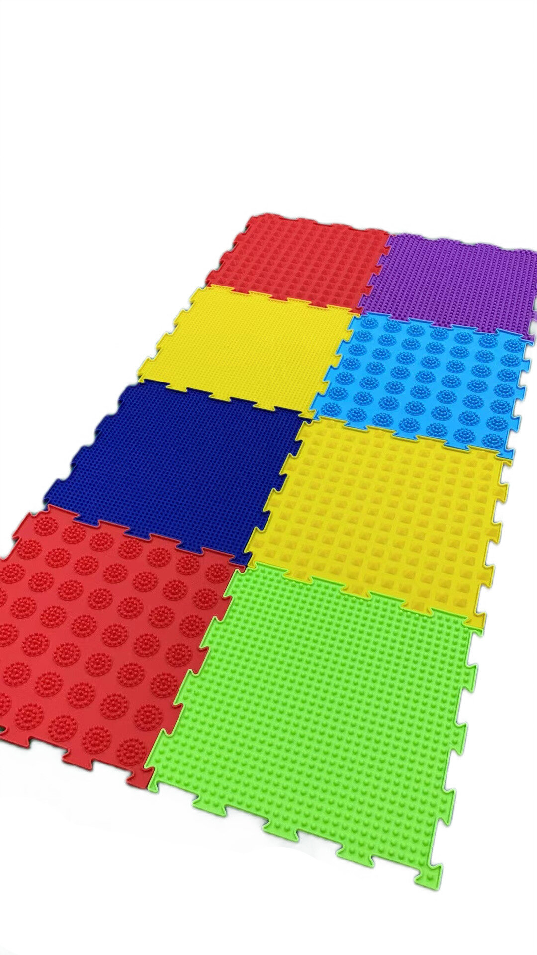 Zestaw ośmiu kolorowych mat ortopedycznych w formie puzzli, każda z wypustkami sensorycznymi. Maty mają różne kolory: czerwony, niebieski, żółty, zielony i fioletowy.