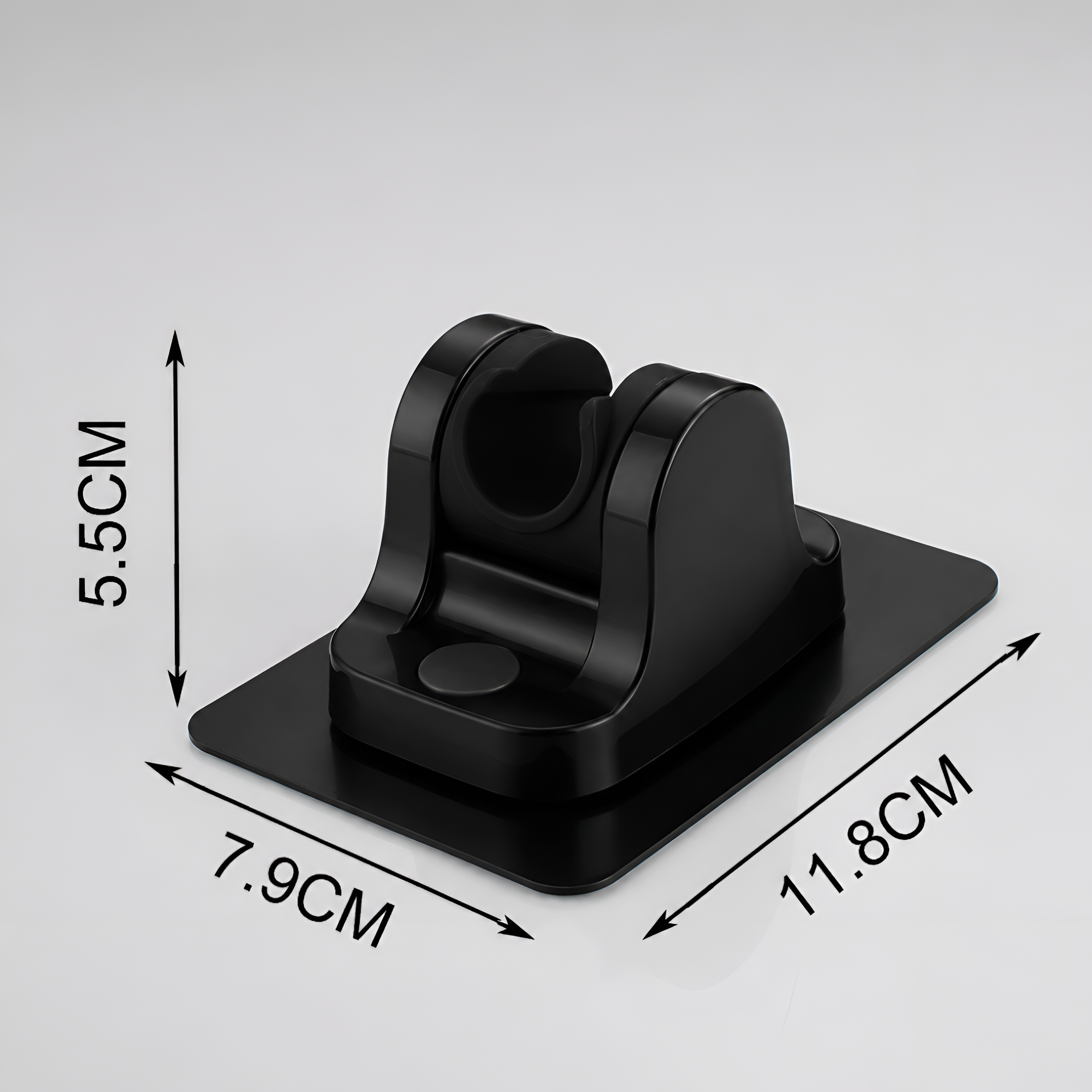 Czarny, plastikowy uchwyt do słuchawki prysznicowej o wymiarach 5.5 cm wysokości, 7.9 cm szerokości i 11.8 cm długości. Uchwyt jest samoprzylepny, co umożliwia montaż bez wiercenia.