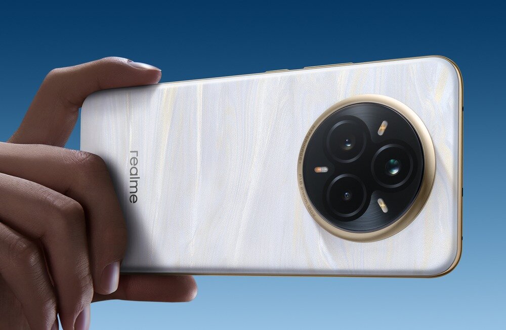 Osoba trzyma smartfon z trzema obiektywami aparatu w okrągłym module. Na obudowie widoczne jest logo \'realme\'.