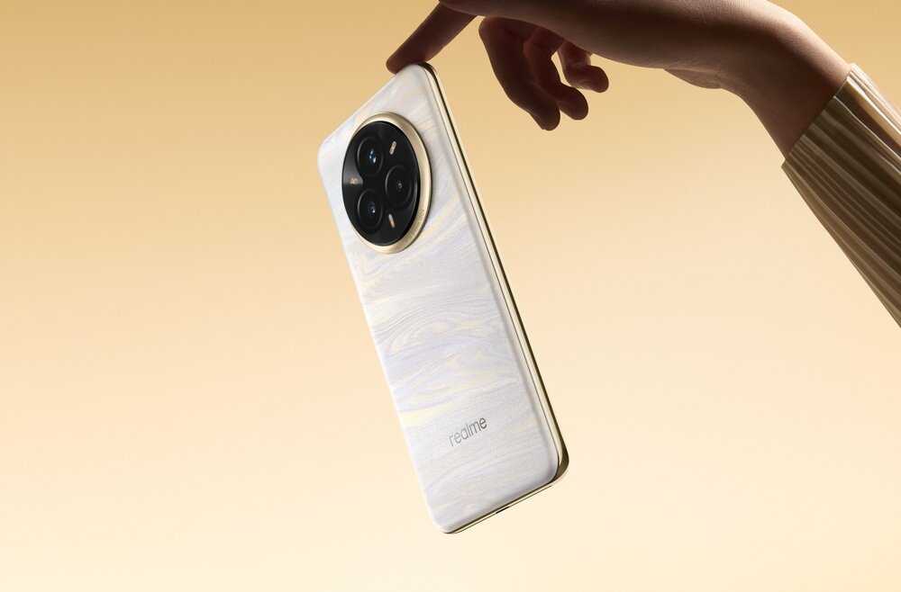 Osoba trzyma smartfon w kolorze szarym z okrągłym modułem aparatu z czterema obiektywami. Na obudowie widoczne jest logo \'realme\'.