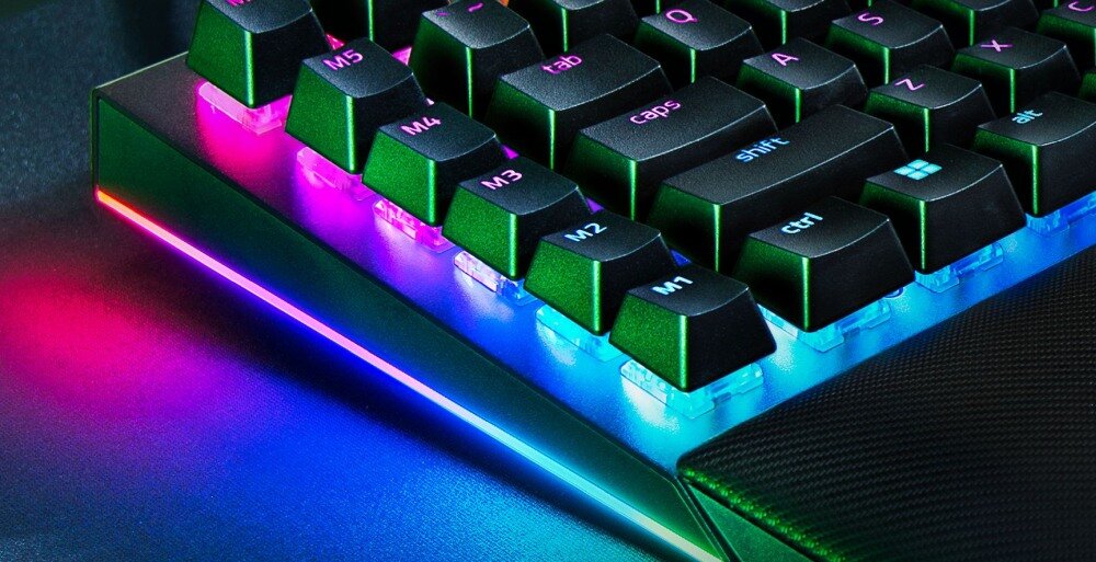 Fragment klawiatury z podświetleniem RGB, widoczne klawisze z oznaczeniami M1, M2, M3, caps, shift, ctrl oraz logo Windows.