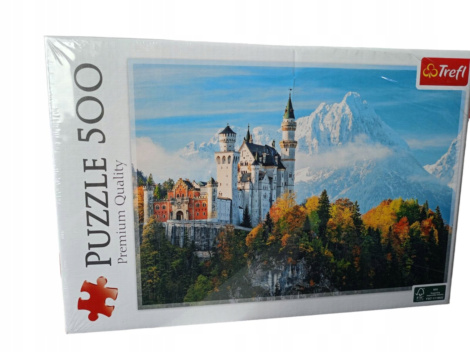 Opakowanie puzzli z obrazem zamku Neuschwanstein na tle gór, z napisem \'PUZZLE 500 Premium Quality\' oraz logo \'Trefl\'.