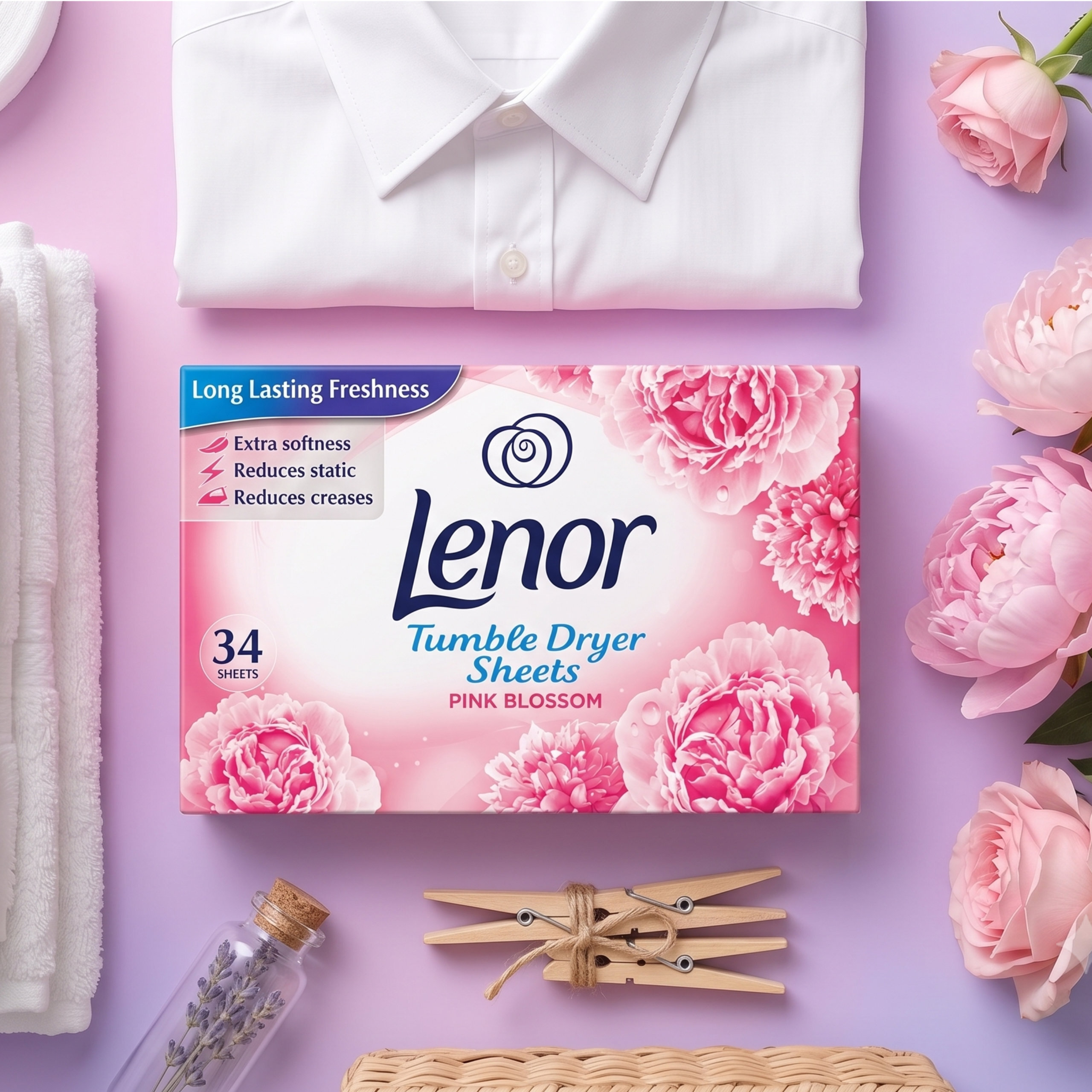 Na obrazie znajduje się opakowanie chusteczek do suszarki Lenor Pink Blossom z napisem \'34 sheets\'. W tle widoczne są kwiaty, koszula, ręcznik, klamerki do bielizny i butelka z lawendą.