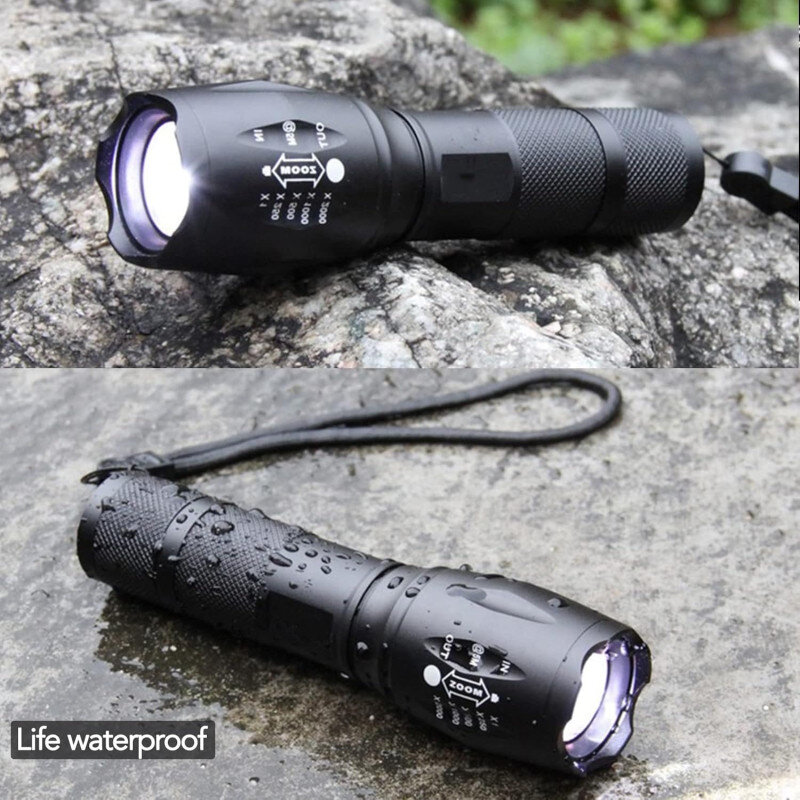 Na zdjęciu widać czarną latarkę LED z napisem \'ZOOM\' i oznaczeniami trybów, leżącą na kamieniu. Obok latarki widoczny jest napis \'Life waterproof\'.