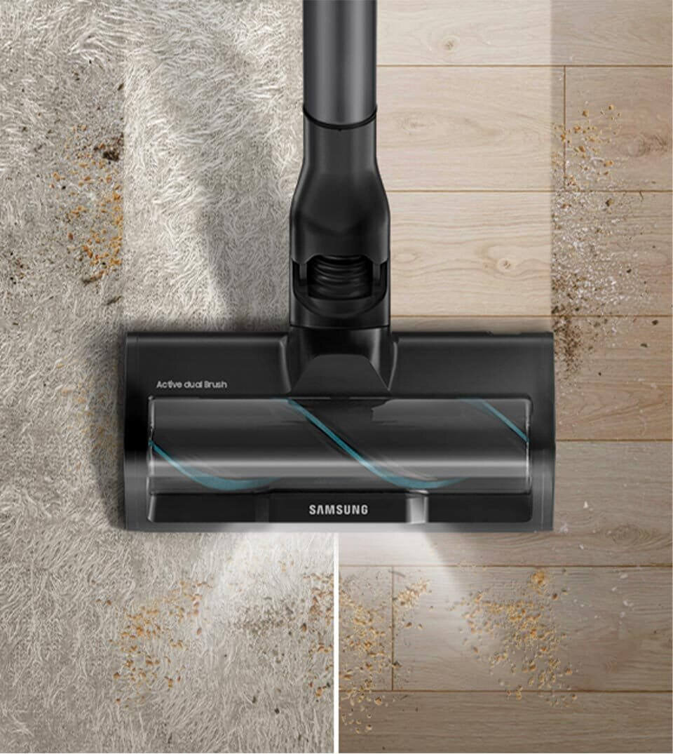 Odkurzacz z napisem \'Active dual brush\' i \'SAMSUNG\' na głowicy, odkurza powierzchnię z dywanu i podłogi drewnianej, usuwając widoczne zabrudzenia.