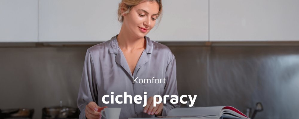 Osoba w szarej koszuli stoi w kuchni, trzymając filiżankę i przeglądając książkę. Na obrazie widoczny jest tekst: \'Komfort cichej pracy\'.
