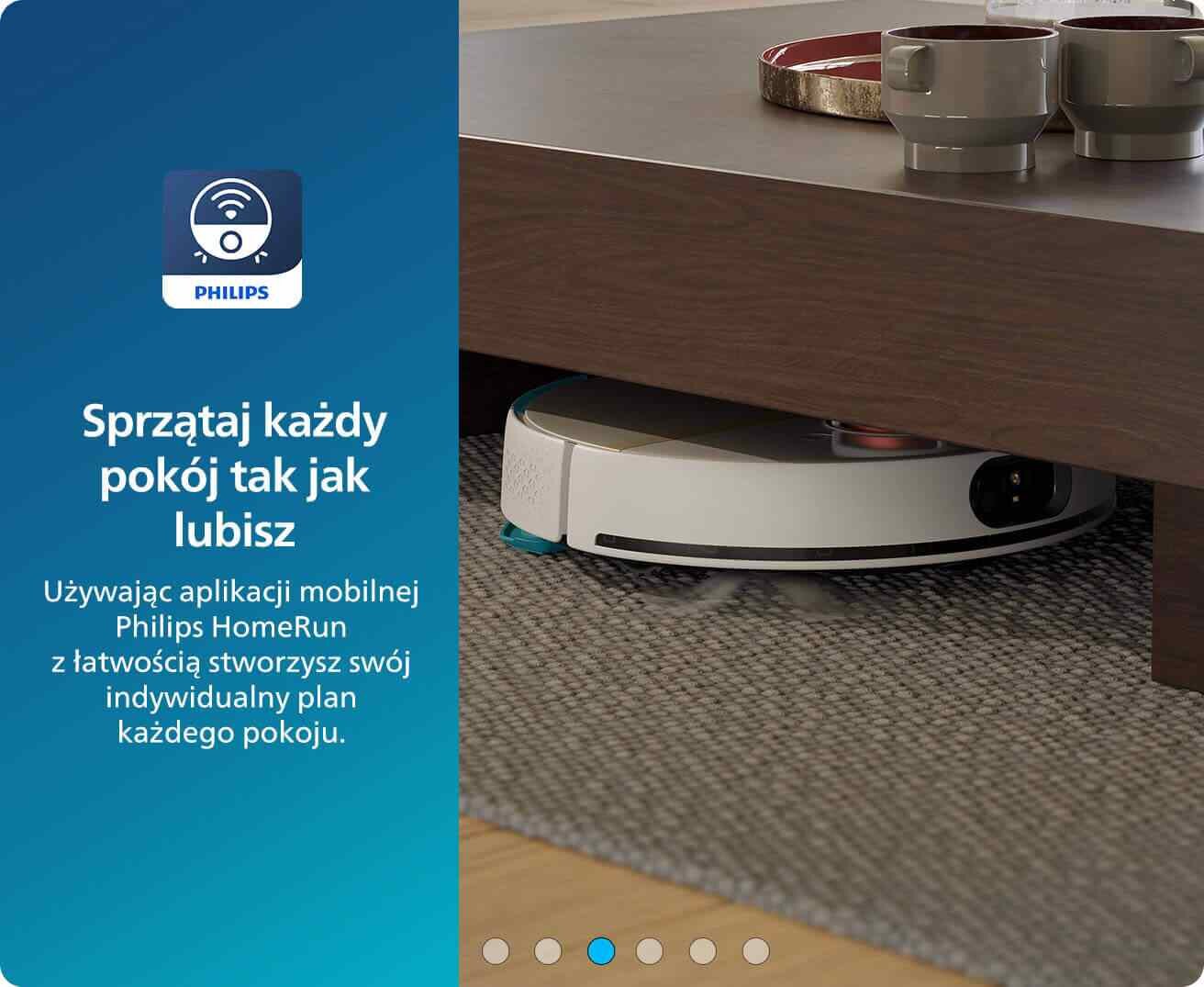 Robot sprzątający znajduje się pod drewnianym stolikiem na dywanie. Obok widoczny jest tekst: \'Sprzątaj każdy pokój tak jak lubisz Używając aplikacji mobilnej Philips HomeRun z łatwością stworzysz swój indywidualny plan każdego pokoju.\'