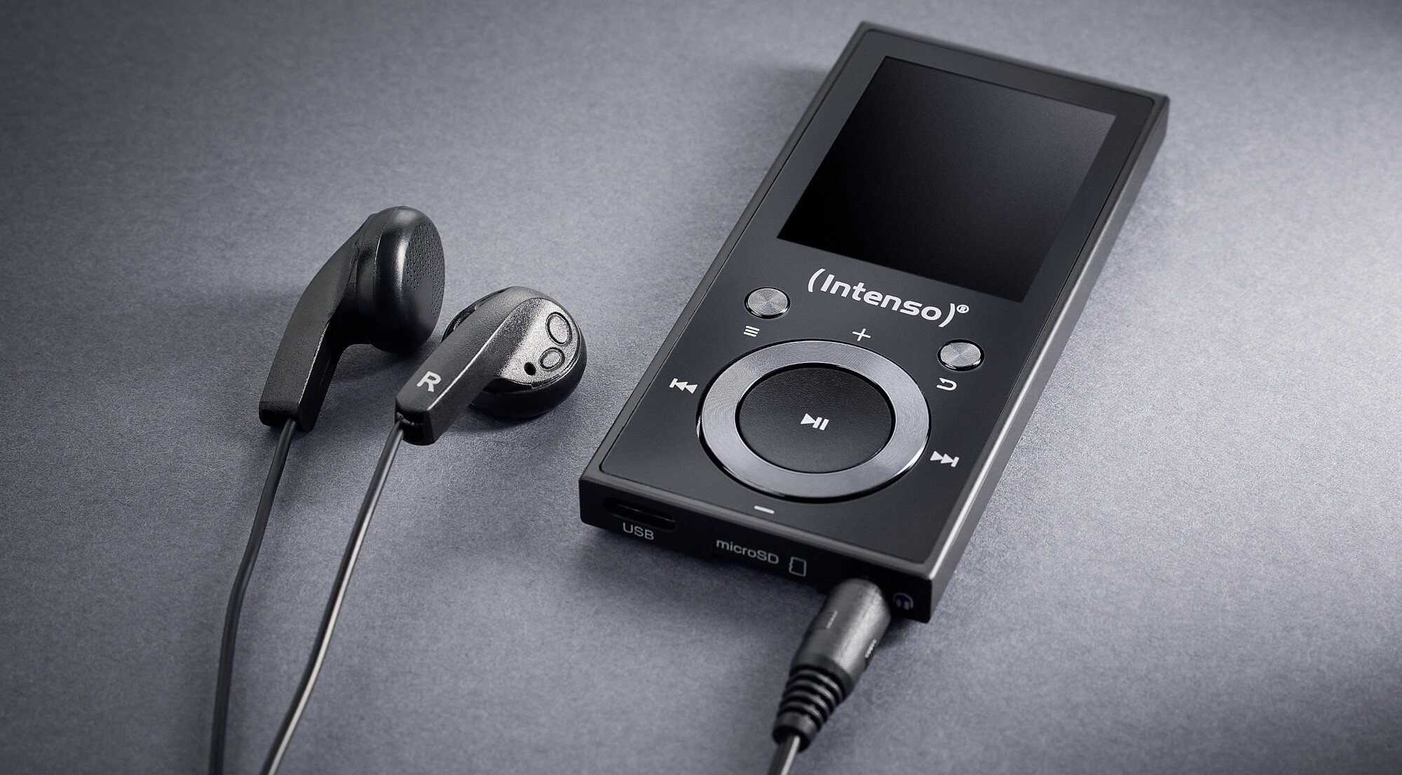 Na obrazie widoczny jest czarny odtwarzacz MP3 z logo \'Intenso\' oraz słuchawki douszne. Odtwarzacz posiada ekran i przyciski sterujące, a także podłączony kabel audio.