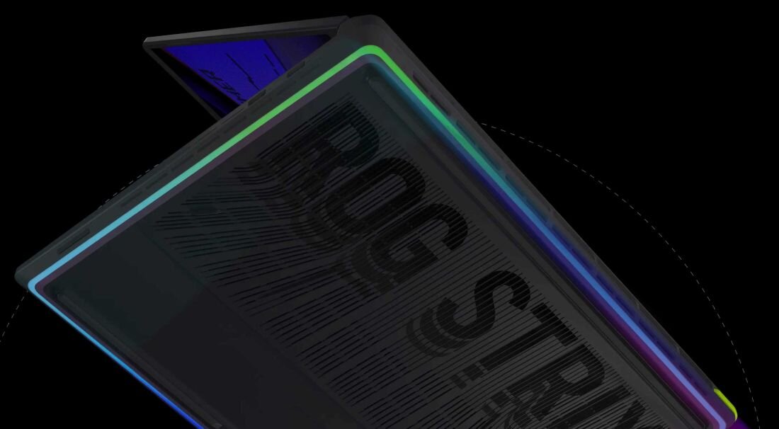 Widoczny jest fragment laptopa z podświetleniem RGB na krawędzi obudowy. Na powierzchni obudowy znajduje się napis \'ROG STRIX\'.