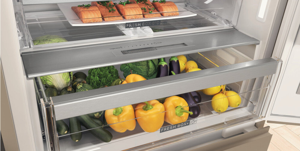 Wnętrze lodówki z widocznymi szufladami oznaczonymi jako \'FRESH BOX\', wypełnionymi warzywami i kawałkami łososia na półce.