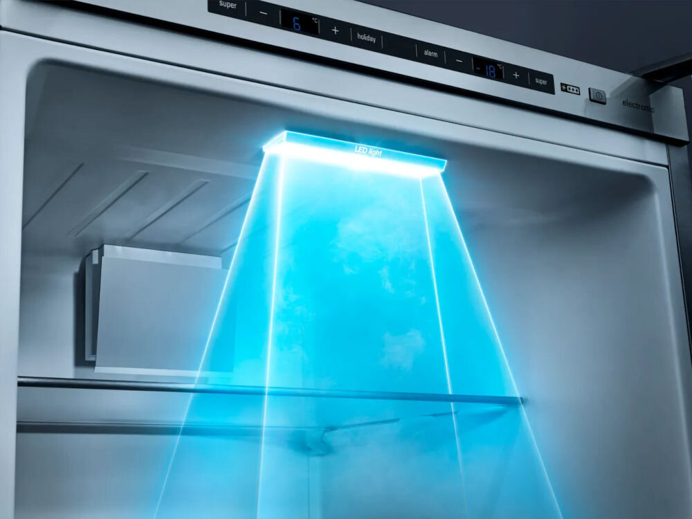 Wnętrze lodówki z niebieskim oświetleniem LED, widoczna półka i panel sterowania z wyświetlaczem temperatury. Na panelu widoczne są napisy: \'super\', \'-16°C\', \'+\', \'holiday\', \'alarm\', \'-18°C\', \'super\', \'LED light\'.