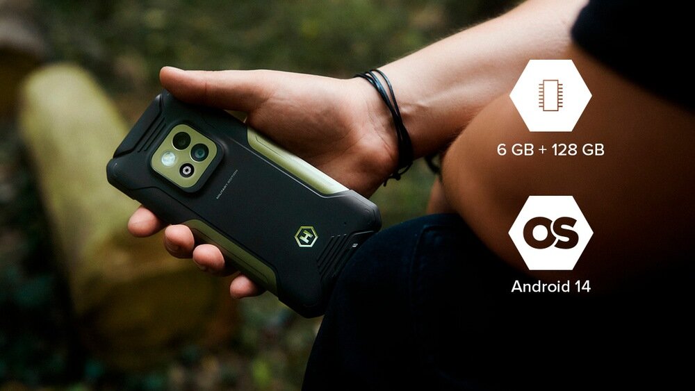 Osoba trzyma smartfon w czarno-zielonej obudowie z widocznym logo. Obok znajdują się ikony z tekstem: \'6 GB + 128 GB\' oraz \'Android 14\'.