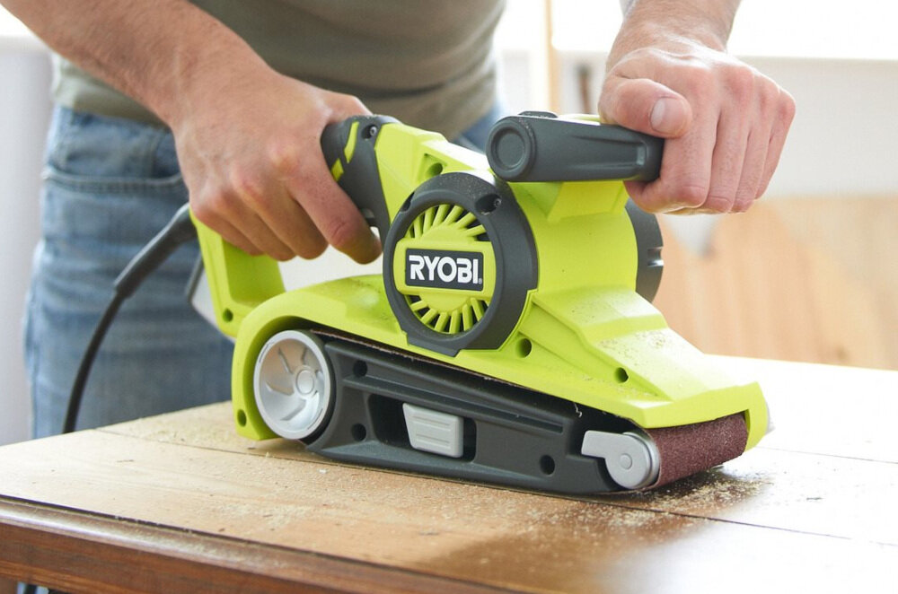 Szlifierka taśmowa RYOBI EBS800 z metalu odpornego na uszkodzenia mechaniczne obudowa i uchwyt pokryte tworzywem sztucznym właściwości antypoślizgowe w domowym warsztacie