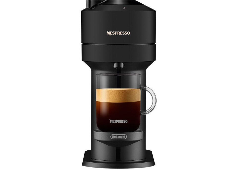 Czarny ekspres do kawy z logo \'Nespresso\' na górze i \'DeLonghi\' na dole, z przezroczystą filiżanką pełną kawy z pianką. Ekspres ma nowoczesny design i cylindryczny kształt.