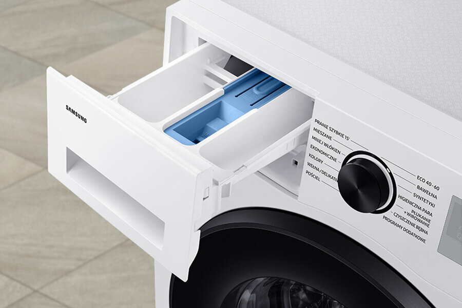 Szuflada StayClean - co warto wiedzieć Zdjęcie przedstawia otwartą szufladę na detergenty w pralce z widocznym logo \'SAMSUNG\'. Obok znajduje się pokrętło z programami prania, takimi jak \'ECO 40-60\', \'Bawełna\', \'Syntetyki\', \'Higieniczna Para\'.
