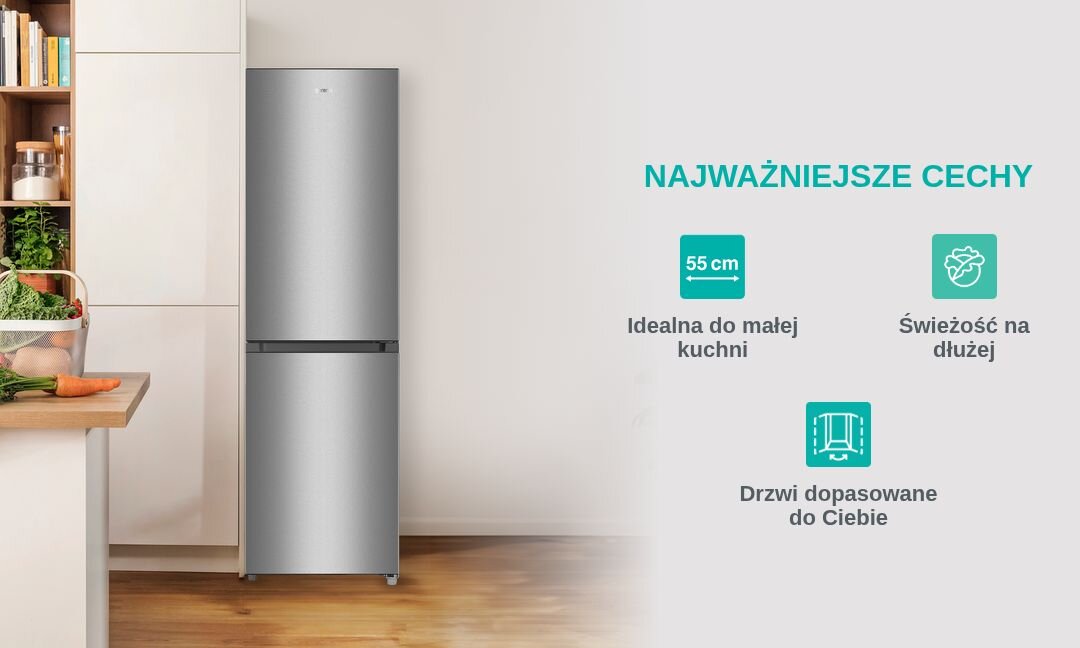 Na obrazie widoczna jest srebrna lodówka stojąca w kuchni obok blatu z warzywami. Obok lodówki znajdują się napisy: \'NAJWAŻNIEJSZE CECHY\', \'55 cm Idealna do małej kuchni\', \'Świeżość na dłużej\', \'Drzwi dopasowane do Ciebie\'.