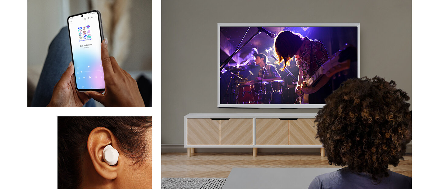 Osoba trzyma smartfon z widocznym ekranem, na którym są kolorowe ikony. Obok, inna osoba ogląda koncert na dużym telewizorze, a w uchu ma białą słuchawkę dokanałową.