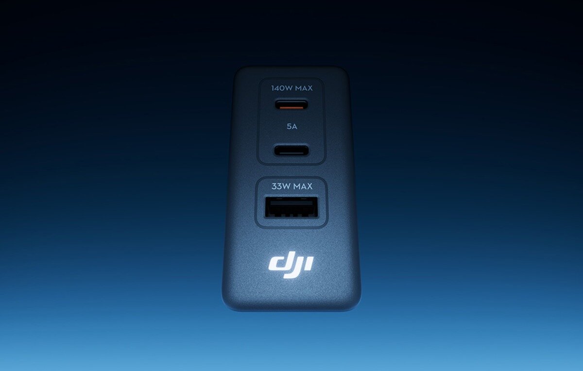 Przedni panel szarej ładowarki DJI z oznaczeniami 140W MAX, 5A, 33W MAX oraz potrójnym portem USB na ciemnym tle