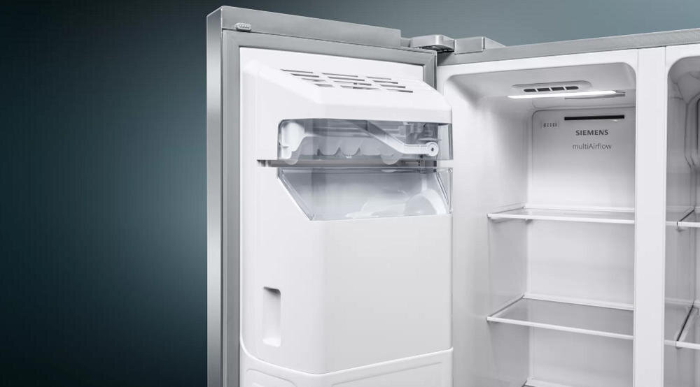 Wnętrze lodówki z widoczną kostkarką i półkami. Na ścianie lodówki znajduje się napis \'SIEMENS multiAirflow\'.