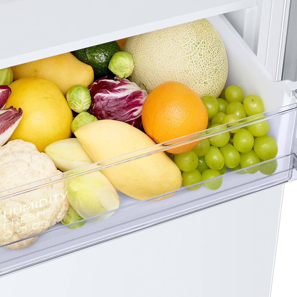 Humidity Fresh - pozwala zachować świeżość warzyw Wnętrze szuflady lodówki wypełnione różnymi owocami i warzywami, takimi jak winogrona, pomarańcza, melon, cytryna, kalafior i brukselka. Na szufladzie widoczny jest napis \'HUMIDITY FRESH\'.