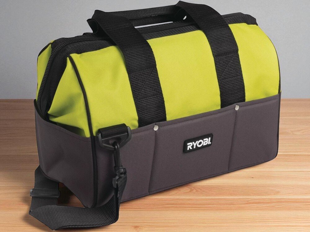 Torba narzędziowa RYOBI UTB4 pomieszczenie drewniany blat torba widoczna od przodu pod skosem stoi na blacie rozmazane tło organizacja pracy praktyczny gadżet mobilność solidność