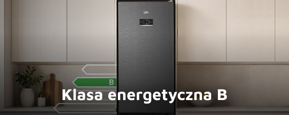 Ciemna lodówka z logo BEKO stoi w kuchni, na której blacie znajdują się dekoracje. Na obrazie widoczny jest napis \'Klasa energetyczna B\'.