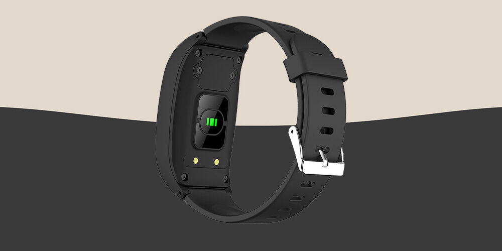 Czarny smartband z metalową klamrą i czujnikiem na spodzie obudowy, widoczny na tle w dwóch odcieniach szarości.