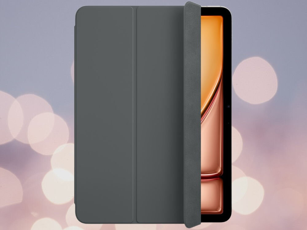 Grafitowe etui na tablet z widoczną częścią ekranu urządzenia w tle. Tło jest rozmyte z jasnymi, okrągłymi światłami.