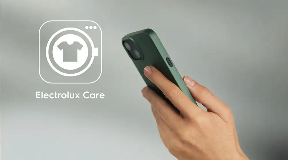 Osoba trzyma zielony smartfon, obok widoczne jest logo z ikoną koszulki i napisem \'Electrolux Care\'.
