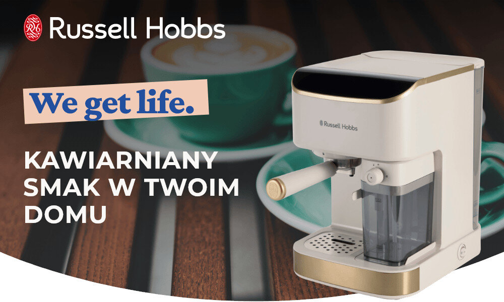Na obrazie widoczny jest kremowy ekspres do kawy z logo Russell Hobbs, obok którego znajduje się filiżanka kawy. Tekst na obrazie: \'We get life. Kawiarniany smak w twoim domu\'.