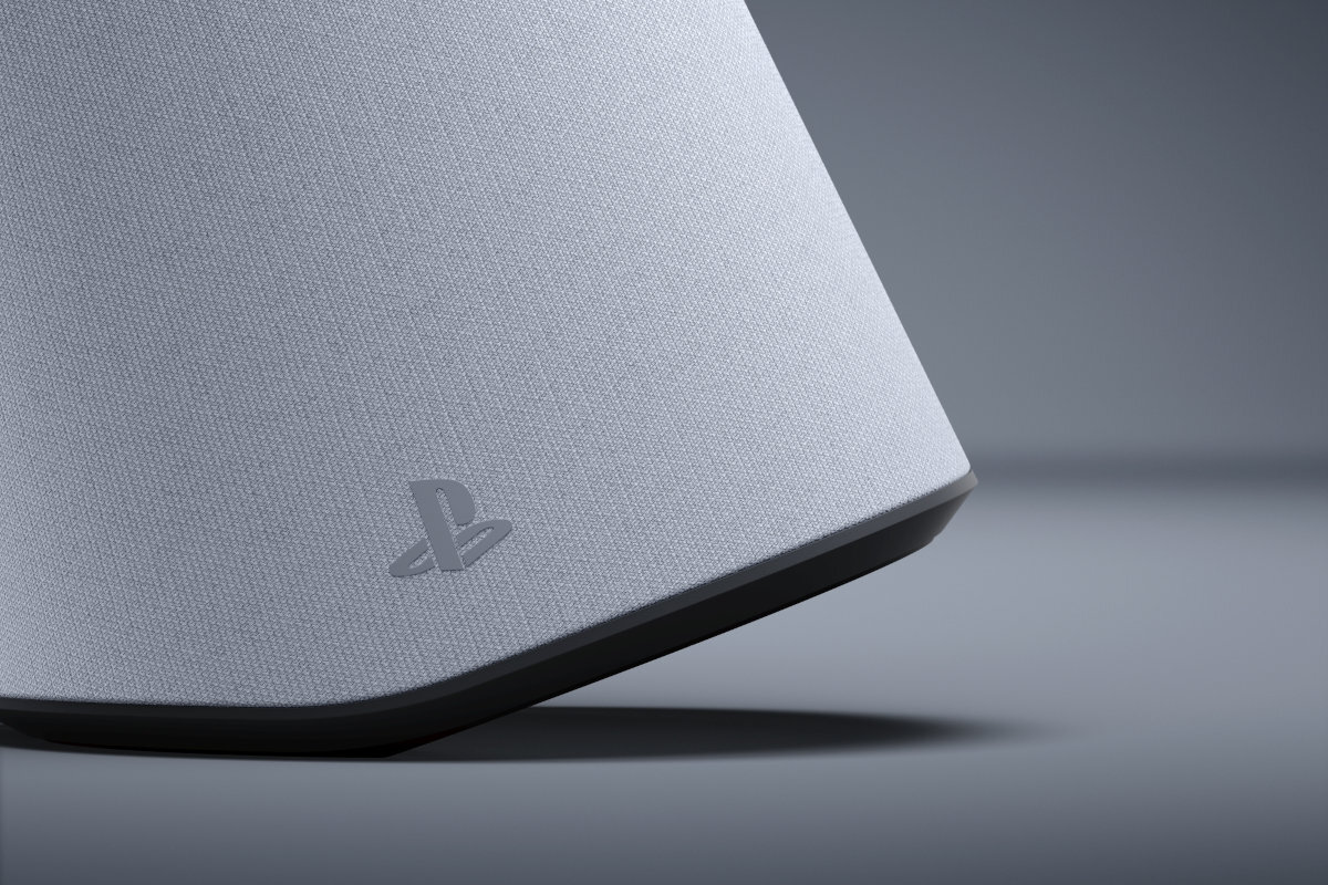Zbliżenie na biały głośnik z widocznym logo PlayStation na powierzchni. Tło jest szare i jednolite.
