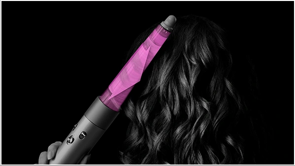 Modelka kręci loki z tyłu głowy, używając multistylera Dyson Airwrap z końcówką stożkową.