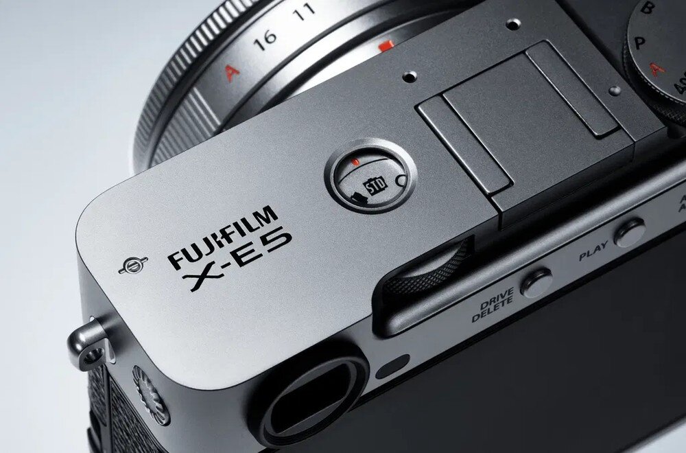 Zbliżenie na górną część aparatu z widocznym logo \'FUJIFILM X-E5\' oraz pokrętłem z oznaczeniem \'STD\'.