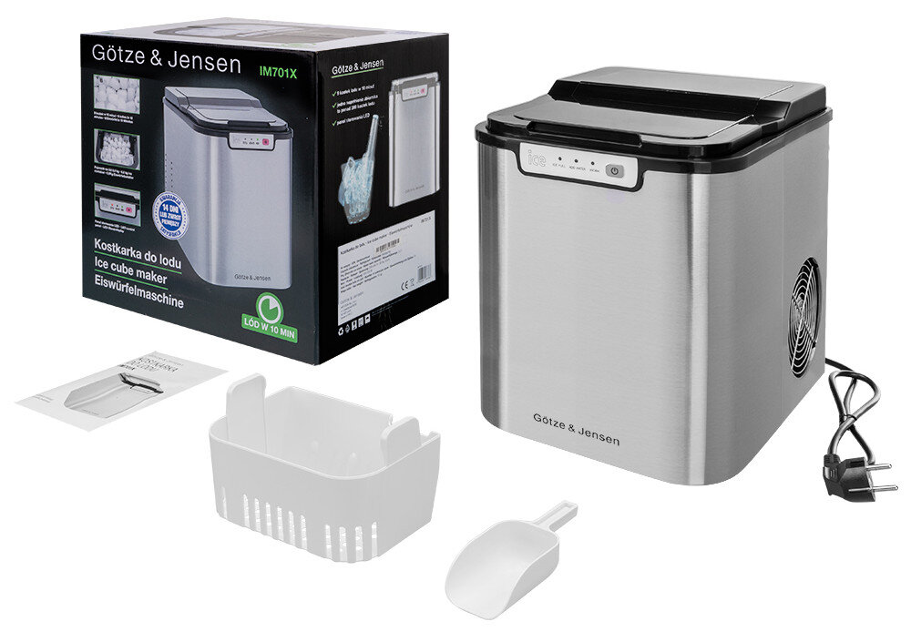 Na obrazie znajduje się kostkarka do lodu Götze & Jensen IM701X Inox z pojemnikiem 2.2 L, obok której leży biały koszyk, łopatka oraz przewód zasilający. W tle widoczne jest opakowanie produktu z grafiką i tekstem: \'Kostkarka do lodu Ice cube maker Eiswürfelmaschine\'.