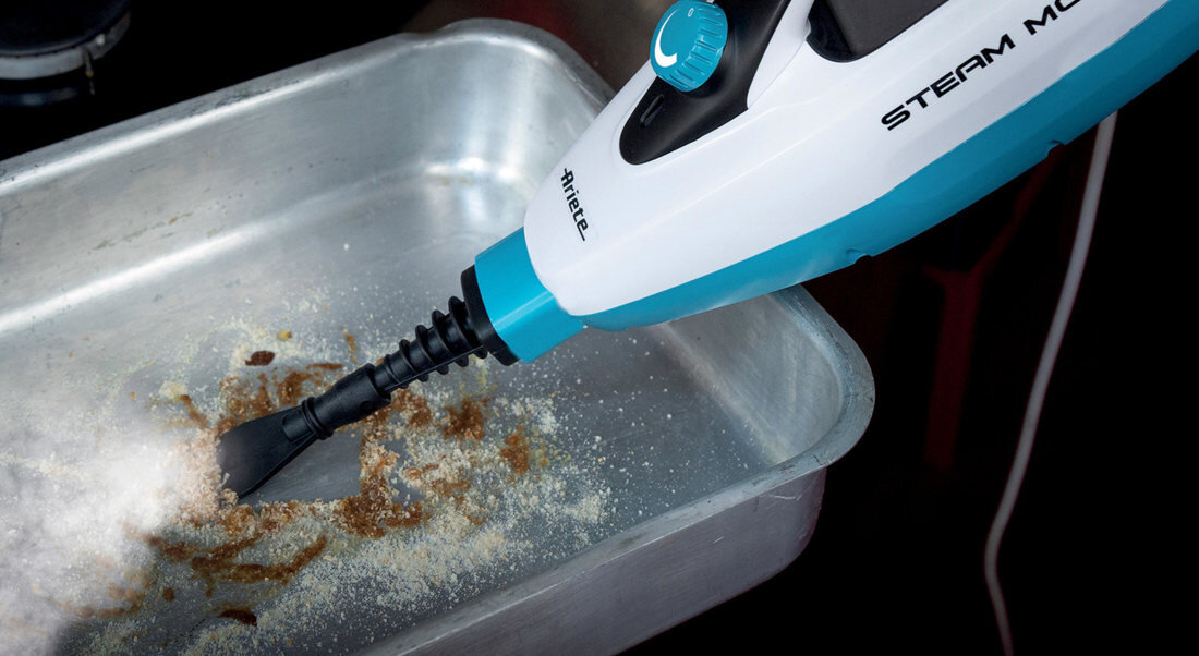 Mop parowy w kolorze biało-niebieskim z widocznym logo \'Ariete\' i napisem \'STEAM MOP\' czyszczący zabrudzoną powierzchnię metalowej tacy.