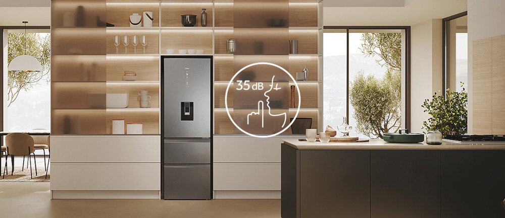 W kuchni znajduje się lodówka w kolorze inox z wyświetlaczem i dozownikiem wody. Na lodówce widoczny jest symbol z napisem \'35 dB\'.