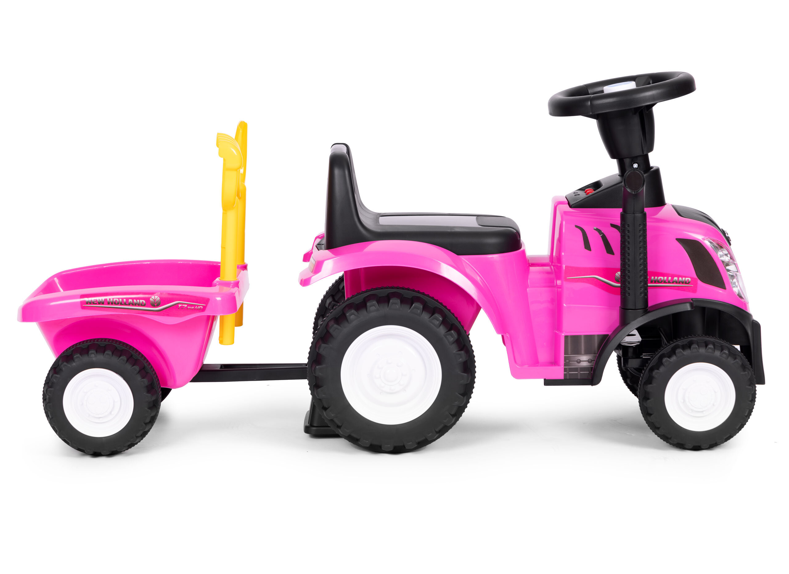 Różowy jeździk w kształcie traktora z przyczepką, posiada interaktywną kierownicę i czarne koła. Na przyczepce widoczne jest logo \'New Holland\'.