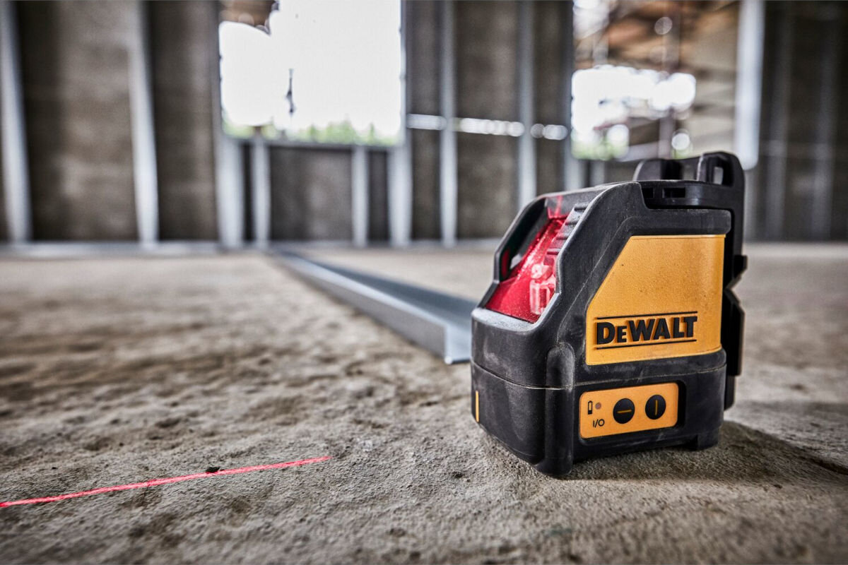 Laser krzyżowy DEWALT DW088K, przyciski, sterowanie, opanowanie, instrukcja, laser stoi na podłodze w remontowanym budynku
