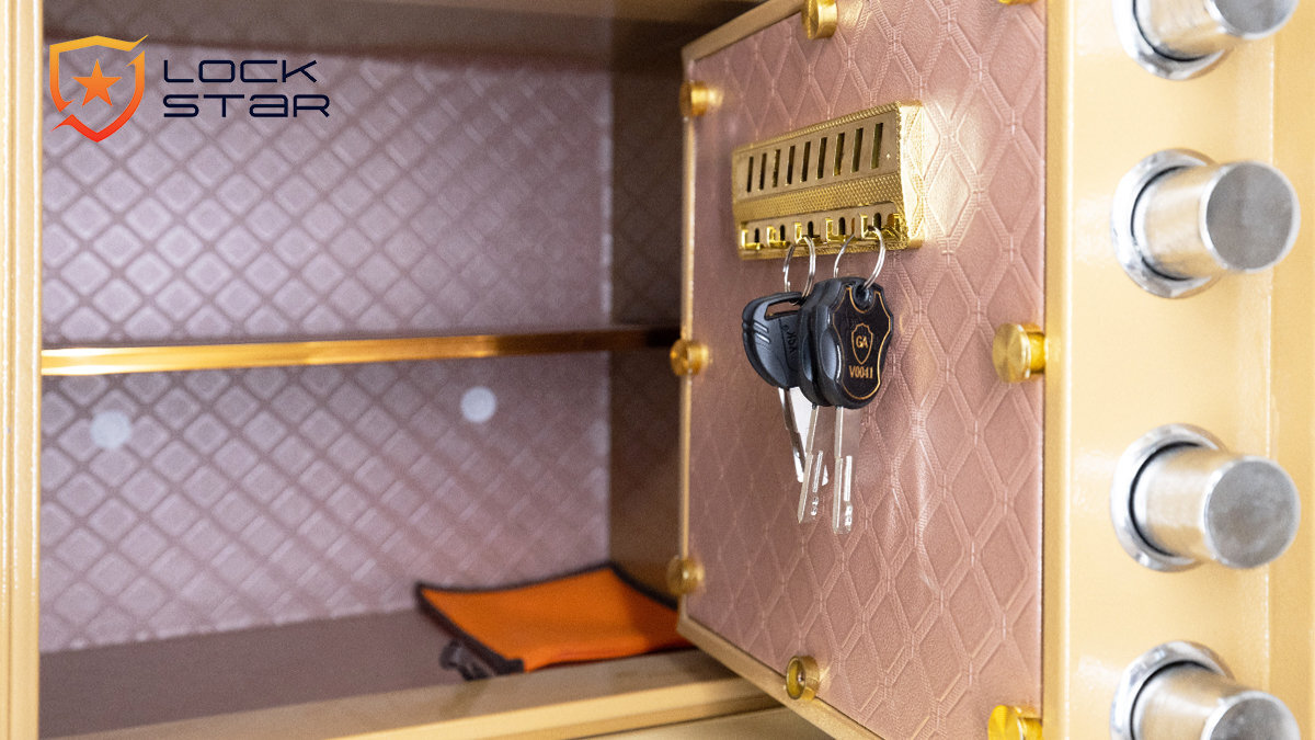 Wnętrze sejfu z widocznymi kluczami zawieszonymi na haczykach oraz logo \'LOCK STAR\' na ścianie. Wnętrze wyłożone jest materiałem o wzorze rombów, a na półce leży pomarańczowy przedmiot.