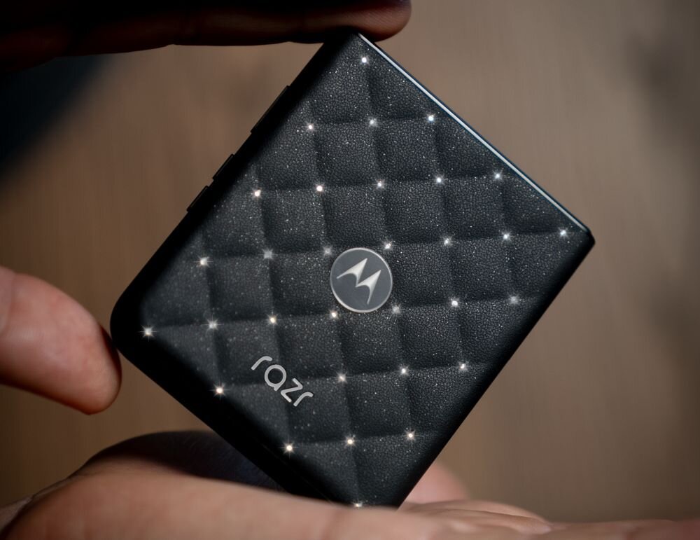 Czarny, kwadratowy telefon z teksturą przypominającą pikowaną powierzchnię, z logo \'M\' i napisem \'razr\'.