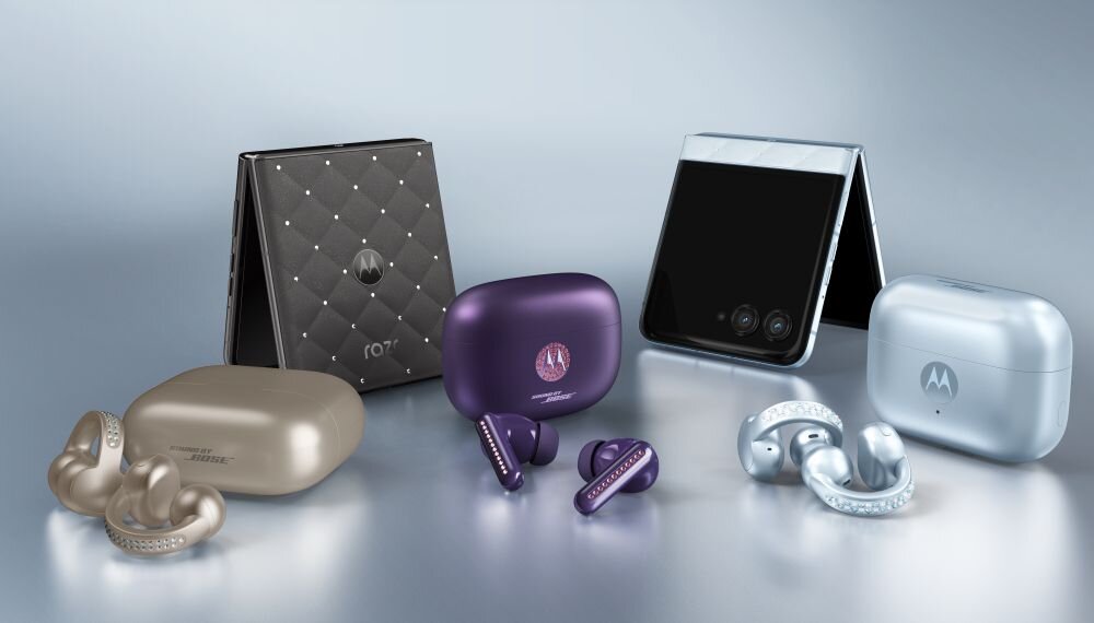 Na obrazie widoczne są dwa składane smartfony oraz trzy pary bezprzewodowych słuchawek z etui. Na jednym z etui widnieje logo \'M\'.
