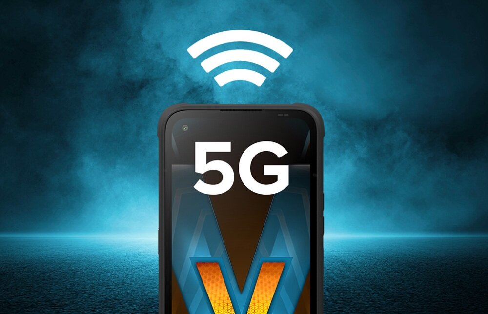 Obraz przedstawia górną część smartfona z wyświetlaczem, na którym widnieje napis \'5G\'. Nad urządzeniem znajduje się symbol sygnału bezprzewodowego na tle niebieskiej, mgiełkowej scenerii.