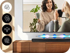 Na obrazie widać telewizor z wyświetlonym obrazem dwóch osób rozmawiających, a poniżej znajduje się soundbar z kolorowymi falami świetlnymi. Obok telewizora widoczne są cztery okrągłe ikony z symbolami: dymek, piłka do koszykówki, mikrofon i film.