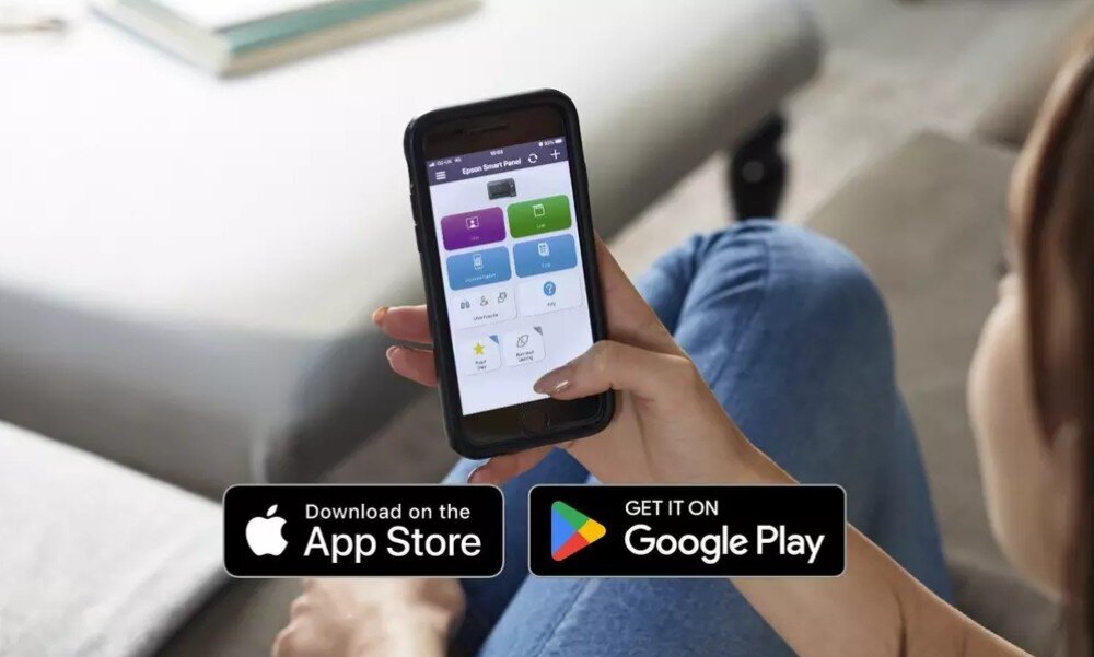 Osoba trzyma smartfon z aplikacją na ekranie, a poniżej widoczne są ikony \'Download on the App Store\' i \'Get it on Google Play\'.